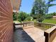 Spacious wooden deck adjacent to a red brick home, surrounded by lush greenery and a clear blue sky at 3323 Baugh St, Raleigh, NC 27604