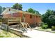 Back of brick home with a wooden deck, concrete patio, and driveway surrounded by lush greenery at 3323 Baugh St, Raleigh, NC 27604