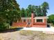Charming red brick home with a brick chimney, white trim, and a large front yard tree at 3323 Baugh St, Raleigh, NC 27604