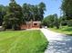 Quaint brick home with a classic chimney, surrounded by lush trees and a well-manicured green lawn at 3323 Baugh St, Raleigh, NC 27604