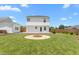 Large backyard with a stone fire pit, green grass, a privacy fence, and two-story white house at 413 Hallie Long Ln, Burlington, NC 27217