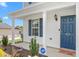 Inviting entrance with a blue front door, cozy covered porch, and landscaped garden beds at 413 Hallie Long Ln, Burlington, NC 27217