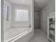 Bright bathroom featuring a soaking tub, shower, decorative glass block window, and storage cabinet at 513 Moultonboro Ave, Wake Forest, NC 27587