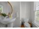 Well-lit half bathroom with a pedestal sink, round mirror, and classic fixtures, adding charm at 513 Moultonboro Ave, Wake Forest, NC 27587