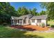 This single-story home features a charming porch, complemented by a stone pathway, lush lawn, and mature landscaping at 514 Lipscomb Grove Church Rd, Hillsborough, NC 27278