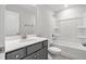 Clean bathroom featuring a gray vanity, sink, mirror, toilet, and bathtub with white wall tiles at 555 Forestville Rd, Wake Forest, NC 27587