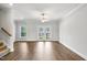 Open-concept living space with hardwood floors, ceiling fan, and bright light from glass patio doors at 555 Forestville Rd, Wake Forest, NC 27587