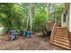 Lush backyard featuring a wooden deck and stairs, along with garbage receptacles and wooded surroundings at 616 Cross Timbers Dr, Durham, NC 27713