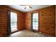 Bedroom with wood paneled walls, two windows, and a ceiling fan at 6600 Sadie Dr, Wendell, NC 27591