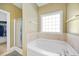 Large soaking tub with a glass block window and a separate shower stall at 82 Finley Ct, Clayton, NC 27520