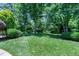 Green grass backyard surrounded by mature trees and manicured landscaping at 9048 Chelsea Dr, Raleigh, NC 27603