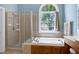 This main bathroom has a glass shower, soaking tub, and a window with nature view at 9048 Chelsea Dr, Raleigh, NC 27603
