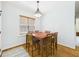 Dining area with a wood table set for six, illuminated by a decorative chandelier and natural light at 100 S Sunset Ridge Dr, Willow Springs, NC 27592