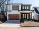 Eye-catching modern home with a stained wood garage door and a combination of white siding and dark brick at 1009 Parker St, Raleigh, NC 27607