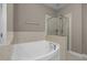 Relaxing soaking tub and shower combination in a stylish bathroom with tiled surround at 1012 Palace Garden Way, Raleigh, NC 27603