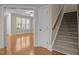 Bright living room with hardwood floors and large windows, leading to a carpeted staircase at 1012 Palace Garden Way, Raleigh, NC 27603