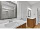 Dual sinks, white counters, and a marble-tiled shower can be seen in the reflection of a square mirror at 125 Davis St, Louisburg, NC 27549