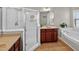 Well-lit bathroom featuring a glass shower, soaker tub, and and vanities with dark wood cabinets and neutral countertops at 1437 Lindenberg Sq, Wake Forest, NC 27587