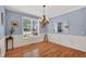 Light-filled dining room with hardwood floors, wainscoting, a stylish chandelier, and a large window at 1437 Lindenberg Sq, Wake Forest, NC 27587