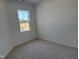 A bright carpeted bedroom featuring a window with view to the construction site at 1563 Wendell Valley Blvd, Wendell, NC 27591