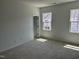 A bright and airy bedroom with neutral carpeting, an ensuite bath and two windows at 1563 Wendell Valley Blvd, Wendell, NC 27591
