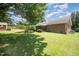 Expansive backyard featuring lush green grass, mature trees, and a glimpse of the home's screened porch at 1822 Atterbury Ln, Durham, NC 27712