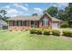 Charming brick home with a manicured lawn, showcasing its inviting front porch and attached garage at 1822 Atterbury Ln, Durham, NC 27712