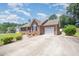 Spacious brick home with an expansive driveway and lush greenery, showcasing its curb appeal and charm at 1822 Atterbury Ln, Durham, NC 27712