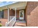Traditional brick home's front porch features a white railing and trim, and a glass paneled front door at 1822 Atterbury Ln, Durham, NC 27712