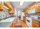 Galley kitchen with light wood cabinets, white appliances, and hardwood floors leading into an adjacent dining area at 1822 Atterbury Ln, Durham, NC 27712