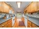Galley kitchen with light wood cabinets, white appliances, and hardwood floors leading into an adjacent dining area at 1822 Atterbury Ln, Durham, NC 27712