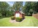 Exterior view of a barn style storage shed with double doors surrounded by green lawn and manicured landscaping at 1822 Atterbury Ln, Durham, NC 27712
