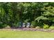 Secluded backyard featuring chairs around a fire pit nestled amongst mature trees and landscaping at 1908 S Lakeshore Dr, Chapel Hill, NC 27514