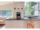 Bright open kitchen with sleek white cabinets, stainless steel appliances, and natural light from large windows at 1908 S Lakeshore Dr, Chapel Hill, NC 27514