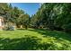 Lush green backyard with a well-maintained lawn, mature trees, and a deck perfect for outdoor gatherings at 210 Peachtree St, Roxboro, NC 27573