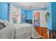 Inviting bedroom with blue textured walls, wood floors, and an open door to another room at 210 Peachtree St, Roxboro, NC 27573
