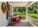 Charming porch featuring a red glider swing, offering a cozy spot to relax and enjoy the outdoors at 210 Peachtree St, Roxboro, NC 27573