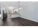 Open dining room with dark floors, modern chandelier, view into the kitchen, and light blue walls at 2106 White Pond Ct, Apex, NC 27523