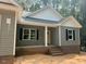 Charming single-story home featuring gray siding, black shutters, and a welcoming front porch with white columns at 211 Rollins Acres Ln, Lillington, NC 27546