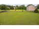 Spacious fenced backyard featuring a large green lawn, mature trees, and play equipment for endless outdoor enjoyment at 265 Beckwith Ave, Clayton, NC 27527