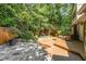 Wood deck and stone patio surrounded by lush landscaping and mature trees for outdoor living at 28 Benchmark, Pittsboro, NC 27312