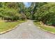 Long gravel driveway lined with green grass and lush, mature trees at 28 Benchmark, Pittsboro, NC 27312