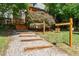 A gravel path and wood step lead to a home surrounded by manicured landscaping and mature trees at 28 Benchmark, Pittsboro, NC 27312