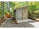 Outdoor shed in wooded area with gravel path, framed by green trees, and offering extra storage at 28 Benchmark, Pittsboro, NC 27312