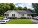 Charming single-story home with well-maintained lawn and landscaping under a partly cloudy sky at 308 E Gilbreath St, Graham, NC 27253