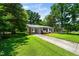 A comfortable single-story home featuring a covered carport and a long driveway, surrounded by greenery at 313 13Th St, Butner, NC 27509