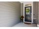 Stylish black front door with wreath, decorative plant, and neutral siding at 405 Bramble Ln, Clayton, NC 27527