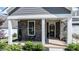 Inviting front porch with stone accents, seating area, and stylish front door at 405 Bramble Ln, Clayton, NC 27527