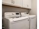 Bright laundry room with modern washer and dryer, complemented by upper cabinets for storage at 405 Bramble Ln, Clayton, NC 27527