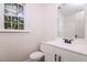 Bright bathroom features a white vanity with dark fixtures, a toilet and a window allowing natural light at 4416 Lancashire Dr, Raleigh, NC 27613